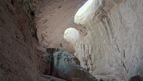 Pan-up-to-Prohodna-Eyes-of-God-enormous-chamber-cave-ceiling-light