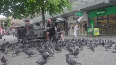 Glaswegian-character-feeding-city-birds,-Sauchiehall-Street,-urban-wildlife