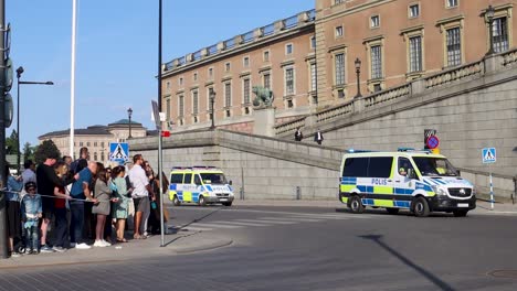 Swedish-police-vans-drive-by-Royal-Palace-on-national-day,-slo-mo