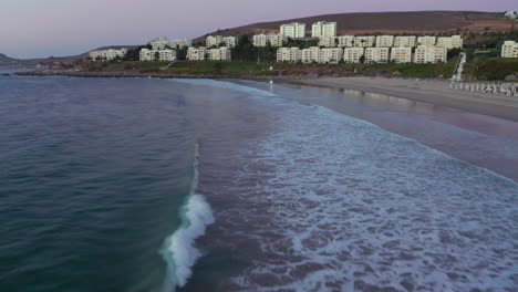 Luftaufnahme-Der-Wellen-Am-Strand-Von-Puerto-Velero-Mit-Ferienwohnungen-Im-Hintergrund