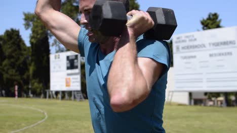 Man-does-overhead-lunges-with-dumbbells-in-his-hands-and-drops-them-on-the-ground-when-he-finishes-the-last-repetition