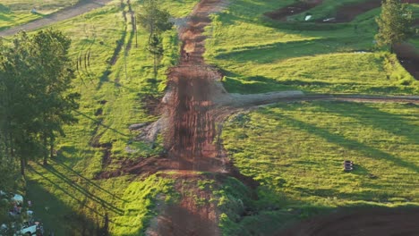 Aerial-panoramic-top-down-view-of-dirtbike-jumping-on-motocross-circuit,-4k-high-quality-slow-motion-drone