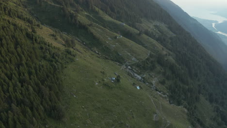 drone-aerial-reveal-of-mountain-grasslands,-lake-in-the-far-background