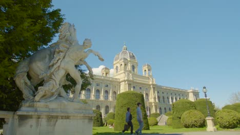 Slow-motion-dolly-shot-tourists-stroll-through-garden-of-Natural-History-Museum,-Vienna