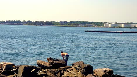 Dos-Hombres-Pescando-En-Las-Rocas-En-La-Bahía-De-Casco,-Portland,-Maine.