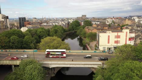 A-smooth-drone-shot-across-a-busy-road,-over-a-city-river-|-The-Water-of-Leith,-Edinburgh,-Scotland-|-Shot-in-4k-at-30-fps