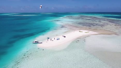 Drone-shot-people-KITESURF-on-turquoise-sea-water,-Los-Roques-Archipelago-Venezuela