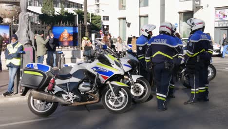 Five-police-officers-in-a-blue-uniform-gather-in-front-of-their-motorbike-parked-to-block-the-street-to-talk-while-a-yellow-jacket-protester-awaits-the-beginning-of-the-demonstration