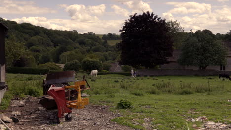 Seen-in-the-clip-is-a-farm,-farm-machinery-and-two-persons-with-a-dog-walking-through