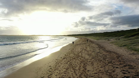 Silhouette-Menschen-Gehen-Am-Goldenen-Sandstrand-Am-Meer-Bei-Sonnenuntergang