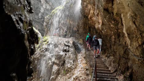 People-Hiking-After-heavy-rain,-water-flows-down-the-cliff-edge-into-the-Höllentalklamm-george-in-bavaria-germany