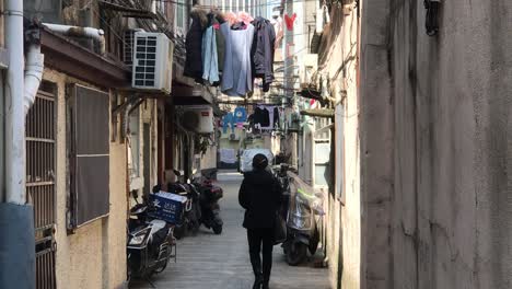 hand-held-shot-of-an-urban-genuine-musty-backyard-area-in-French-Concession,-Shanghai-on-a-cold-sunny-blue-sky-day-with-laundry-hanging-on-the-balconies-and-beteen-the-narrow-houses