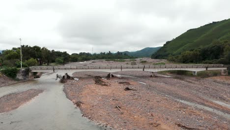 A-bridge-over-the-La-Caldera-River-in-Salta,-Argentina,-on-a-summer-day-with-low-water-flow