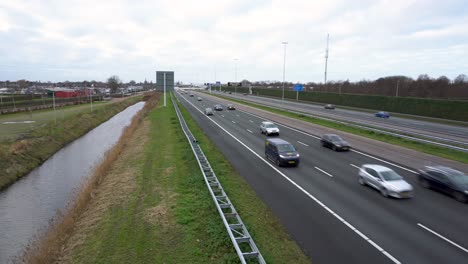 Vehicles-travelling-on-Dutch-highway,-camera-pan-from-roadside-verge