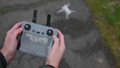 Close-up-of-drone-controller-as-operator-turns-on-and-launches-quadcopter-from-ground