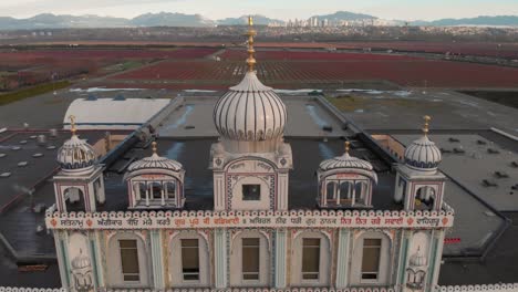 Drone-4K-Footage-front-facade-of-Sikh-temple-with-beautiful-and-elaborate-sculpture-and-symmetrical-architecture-revealing-the-blueberry-farmland