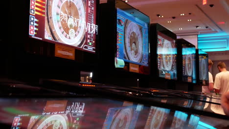 Bewegung-Von-Menschen,-Die-Casino-Roulette-An-Einem-Automaten-Spielen,-Mit-Spiegelung-Einer-Sich-Drehenden-Kugel-Auf-Dem-Bildschirm-Im-Casino