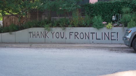 Static-shot-of-Thank-You,-Frontline-wall-art-mural-in-Austin,-Texas-while-two-bikers-ride-by