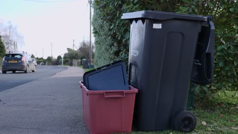 Leere-Recyclingbehälter-Mit-Autofahren-Im-Hintergrund