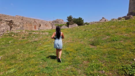 Atractiva-Mujer-Joven-Caminando-En-El-Patio-Del-Antiguo-Castillo-En-Grecia