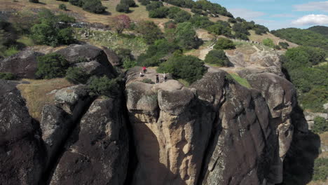 A-group-of-male-friends-relaxing-on-top-of-Meteora-rock-formation-pillars-sunny-day