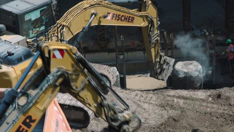 Excavator-breaking,-digging-and-loading-stone-into-truck-CloseUp-construction