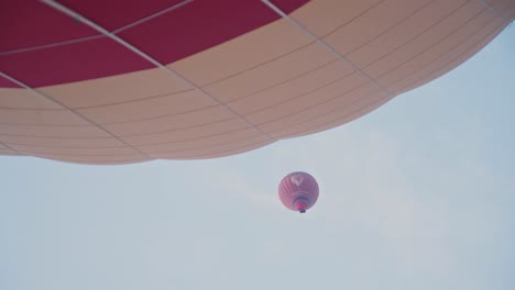 Heißluftballon-Fliegt-Darüber,-Während-Ein-Anderer-Ballon-Vorbereitet-Wird,-Handansicht