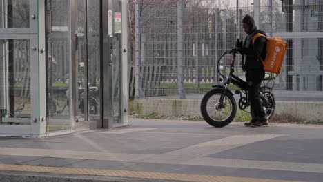 Jinete-De-Comida,-Repartidor-Con-Bicicleta-Esperando-Un-Tren-En-La-Estación