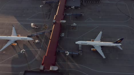 Zwei-Große-Flugzeuge-Verstauben-Vor-Den-Toren-Aufgrund-Einer-Globalen-Pandemie-In-Der-Abenddämmerung,-Drohne