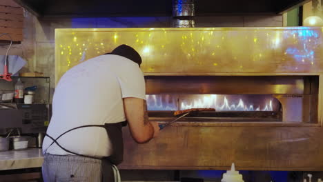 Un-Hombre-Girando-Una-Pizza-En-Un-Horno-De-Pizza