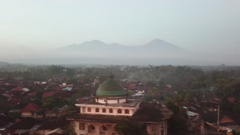 Mezquita-Aérea-De-4k-De-Gran-Pueblo-En-Indonesia,-Toma-Panorámica-Lateral-Con-El-Monte-Rinjani