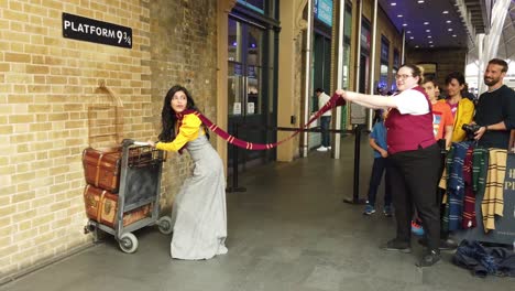 Woman-posing-at-the-Harry-Potter-platform-9-and-3-4-tourist-attraction,-King's-Cross-station,-London,-England,-UK