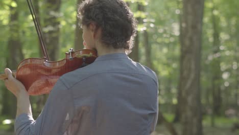 Primer-Plano-Detallado-Del-Violinista-Tocando-El-Violín-Actuando-En-Medio-Del-Bosque