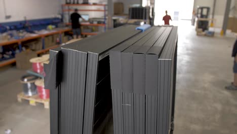 Placing-foam-separation-bumper-on-solar-panels-before-shipping-at-warehouse-with-employees,-Handheld-closeup-shot