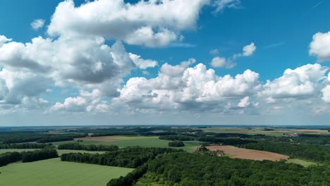 Malerische-Luftaufnahme-Des-Dorfes-Dagny,-Frankreich-Mit-Ausgedehnten-Grünen-Feldern-Und-Flauschigen-Weißen-Wolken