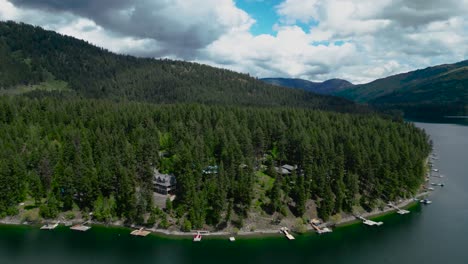 Aerial-video-from-a-drone:-Mountain-lake,-boat-fishing,-pine-forest,-forest-homes-with-docks-in-Canada