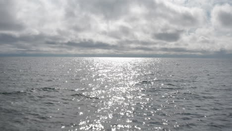 Vista-Aérea-De-Drones-Volando-Sobre-Pequeñas-Rocas-Que-Se-Asoman-Entre-Las-Olas-En-El-Lago-Superior,-Revelando-Olas-En-El-Agua-Hasta-El-Horizonte-En-Un-Día-Nublado