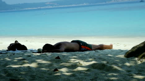 Hombre-Durmiendo-En-Una-Playa-De-Arena-Blanca-En-Las-Islas-Perhentian,-Malasia-Durante-El-Día-Soleado---Plano-General-1080p-60p