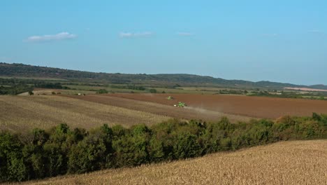 Aerial-drone-shot-of-John-Deere-tractor-harvesting-sunflower-seeds-during-summer-evening