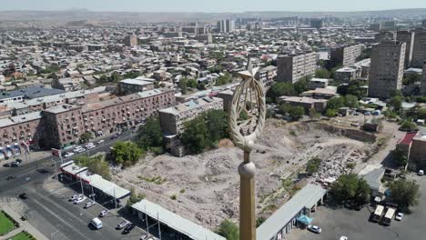 Aerial-flies-past-old-Soviet-Armenian-crest,-Yerevan-Armenia-cityscape