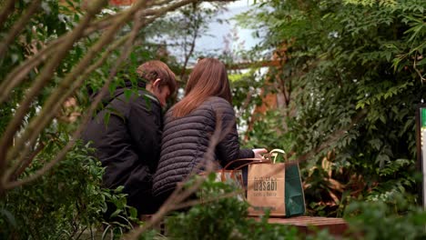 Pareja-Joven-Disfrutando-De-Un-Almuerzo-En-El-Parque-De-Canary-Wharf,-Londres,-Reino-Unido