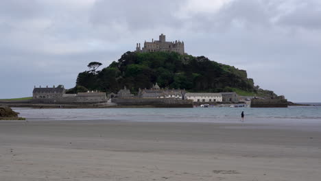 Solitary-person-running-on-the-beach-toward-the-sea-of-Marazion-in-Cornwall-right-in-front-of-Mount-St-Michael