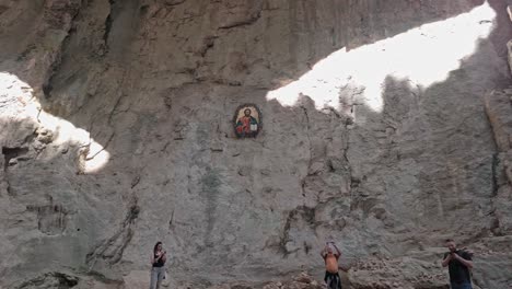 Los-Visitantes-Ven-La-Luz-De-Los-Ojos-De-Dios-Brillar-En-La-Pared-De-La-Cueva-Con-Un-ícono-Religioso.