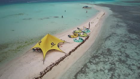 Kitesurfers-set-up-camp-on-a-small-sandbar-in-the-turquoise-waters-of-Los-Roques,-aerial-view