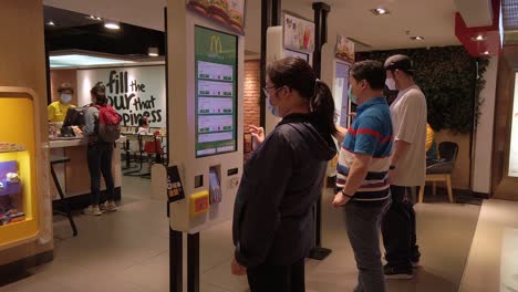 Corona-Virus-Pandemic,-Locals-using-Mcdonalds-self-service-order-screens-wearing-protective-face-masks-in-downtown-Hong-Kong