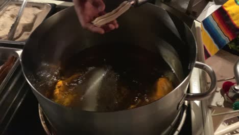 Fresh-churros-being-made-by-hand-and-fried-in-a-pot-of-bubbling-hot-oil