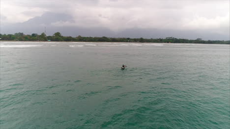 AERIAL:-Honduran-fisherman-on-canoe-paddling-towards-the-beach---El-Porvenir,-Honduras-1