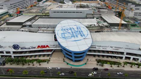 Eine-Seitliche-Kamerafahrt-Durch-Die-SM-Mall-Of-Asia,-Während-Autos-Am-Eingang-Am-Strand-Vorbeifahren