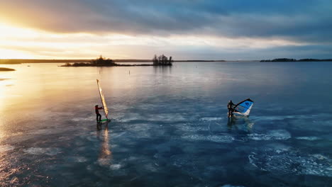 Two-ice-windsurfers-on-frozen-lake-in-colorful-sunset