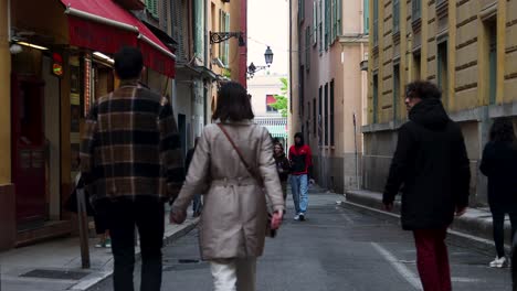 People-walking-in-narrow-street-of-old-town-Nice,-France,-Static-view